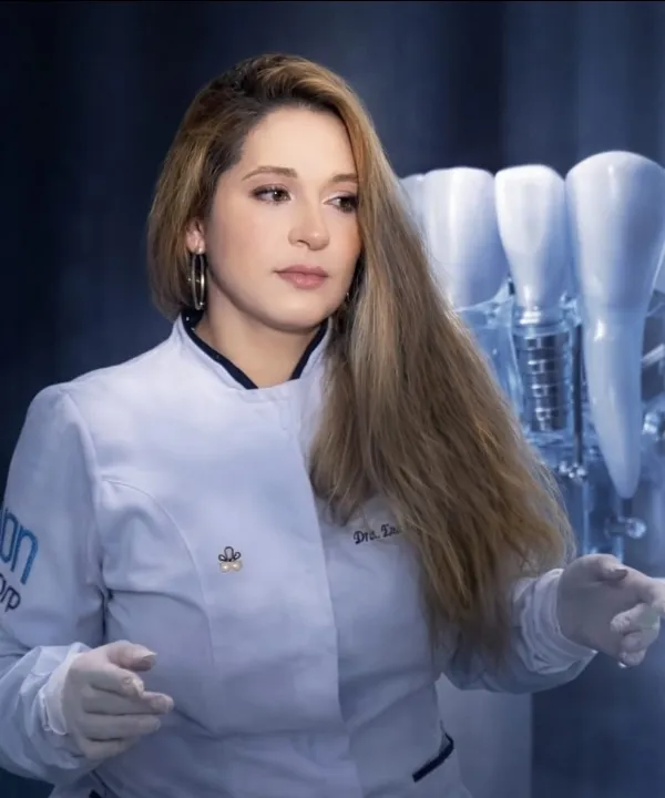 Dra. Ena Dávila Black con uniforme clínico junto a modelos de implantes dentales